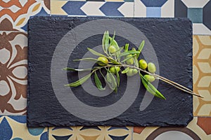 Green and black olives with leaves on dark background. Copy space, flat lay