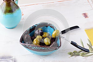 Green and black olives in olive oil in a traditional Greek bowl