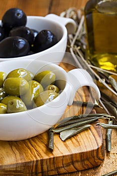 Green and black olives in olive oil on wooden rustic board .Ital