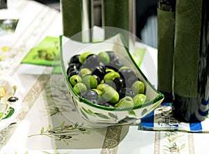 Green and black olives in porcelain plate on a table
