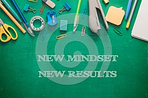 Green blackboard with stationery and text New Mindset New Results