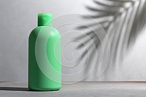 Green blank packaging cosmetic bottle with shadow of palm leaves