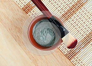 Green blue bentonite clay powder in the bowl and make-up brush. Clay texture close up. Diy facial mask and body wrap recipe. photo