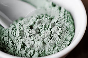 Green (blue) bentonite facial clay (alginate mask, body wrap) in a bowl. Clay texture close-up