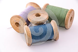 Green blue purple white sewing thread on white background isolated