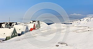 Green, blue, red and green inuit houses covered in snow at the f