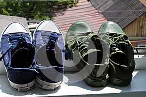 Green and blue sneakers are dried in the sun