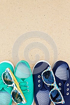 Green and blue sneakers and sunglasses on brown background