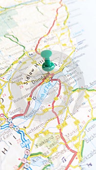 A green board pin stuck in Dundee on a map of Scotland portrait photo