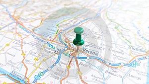 A green board pin stuck in Verona on a map of Italy