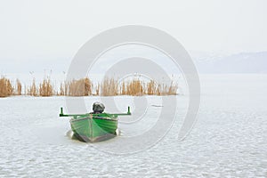 Green boat trapped in frozen lake