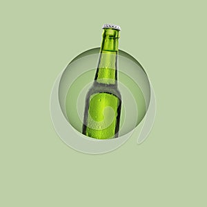 Green bottle of fresh beer with drops of condensation on pastel green background