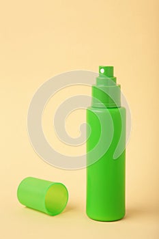 Green bottle of insect repellent spray on beige background. Vertical photo