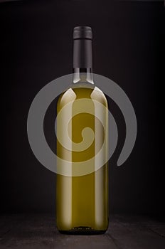 Green bottle of white wine mock up on elegant dark black wooden background, vertical.
