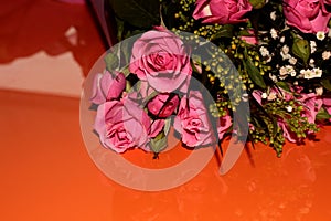 Green bouquet with small roses on an orange background. Pink small roses