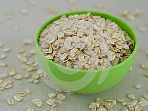 Green bowl full of oatmeal with oats around it