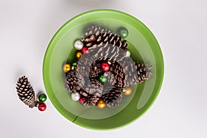 Green bowl of pinecones multi colored Christmas ornaments