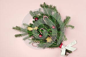 Green Branches Fir Tree With Christmas Decorated With Candy Canes Red Balls and Gingerbread Cookies on Pink Paper Background Top
