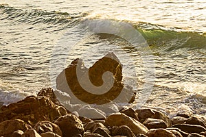 Green breaking wave on rocky shoreline in california