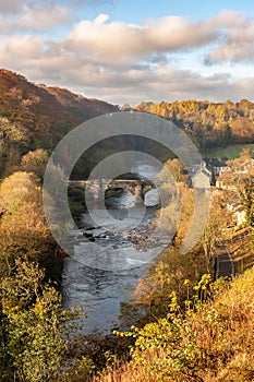 The Green Bridge over the River Swale as seen from the Castle Walk on a vibrant autumn afternoon in golden sunlight