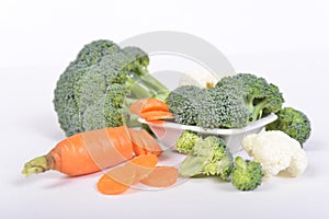 Green broccoli and carrot cut in piecies lying on white background