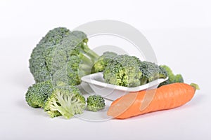 Green broccoli and carrot lying on white background