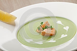 Green broccoli cream soup puree with filleted salmon and lemon