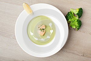 Green broccoli cream soup puree with filleted salmon and lemon