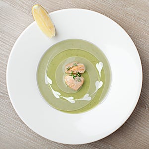 Green broccoli cream soup puree with filleted salmon and lemon