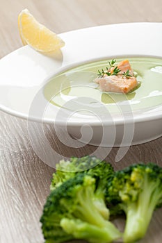 Green broccoli cream soup puree with filleted salmon and lemon