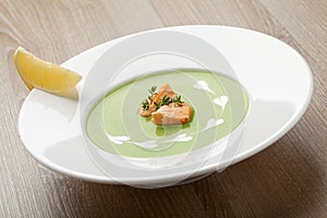 Green broccoli cream soup puree with filleted salmon and lemon photo