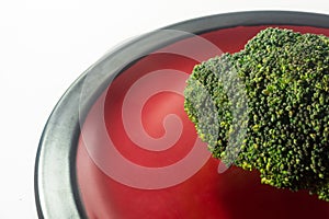 Green Brocolli on Red and Black Plate on White Background