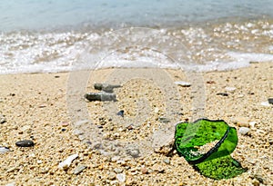 Green broken glass fragments lay on the beach at midday at Cape Panwa, Phuket, Thailand, Dangerous for tourists who pass by