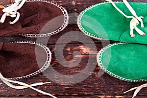 Green and brown suede espadrille shoes on wooden background.