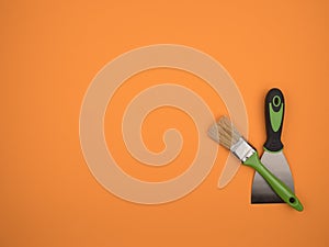 Green brush and spatula on an orange background