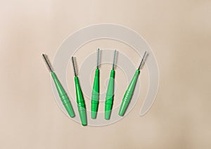 Green Brushes for braces toothbrushes for interdental spaces on beige background The concept of good hygiene