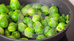 Green brussels sprouts sizzles and simmers on a stove. Selective focus