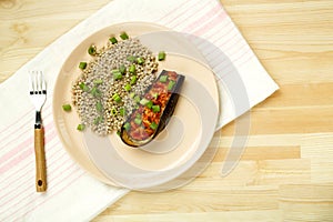 Green buckwheat with baked eggplant with tomato and garlic on a plate on a linen napkin and a fork.