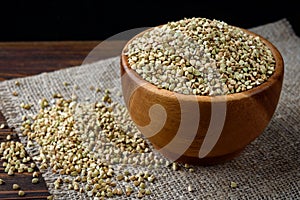 Green buckwheat in wooden bowl on wooden background.