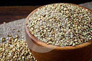 Green buckwheat in wooden bowl on wooden background.