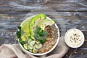 Green Buddha Bowl with lentils, quinoa, avocado, cucumber, fresh lettuce, herbs and seeds