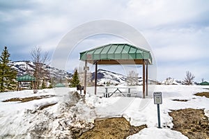 Green cabana with barbecue grill and picnic table at a snow covered park