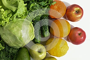 Green cabbage, parsley, cucumbers, salad, avocado, apple, orange orange, mandarin, yellow lemon, red apples on a white wooden