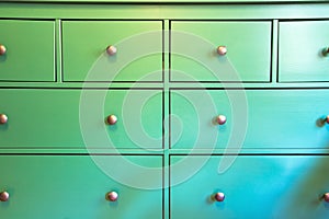 Green cabinet with various drawers, colorful wooden closet close-up retro design background texture