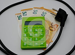 A green calculator on top of some banknotes with a household electric cable nearby