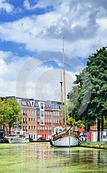 Green canal with yachts and apartment buildings, Gouda, Netherlands.