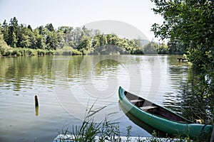 Green canoe boat parked by a lake shore