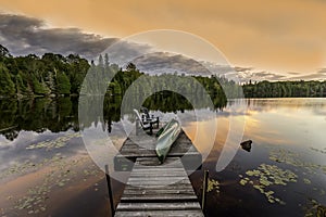 Green Canoe and Chairs on a Dock at Sunset