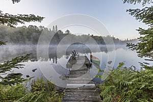 Green canoe and dock on a misty morning - Ontario, Canada