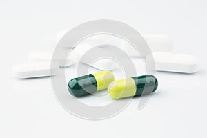 Green capsules and white antibiotic pills.